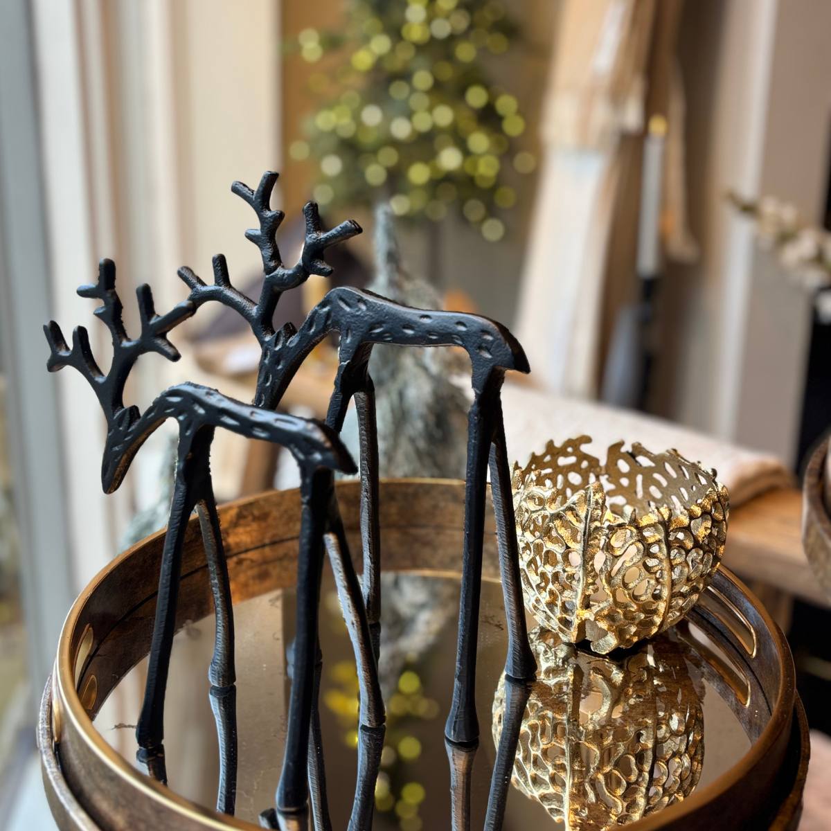 Decorative black metal Jackson deer figurines on a reflective surface with a gold bowl in the background - Two sizes shown