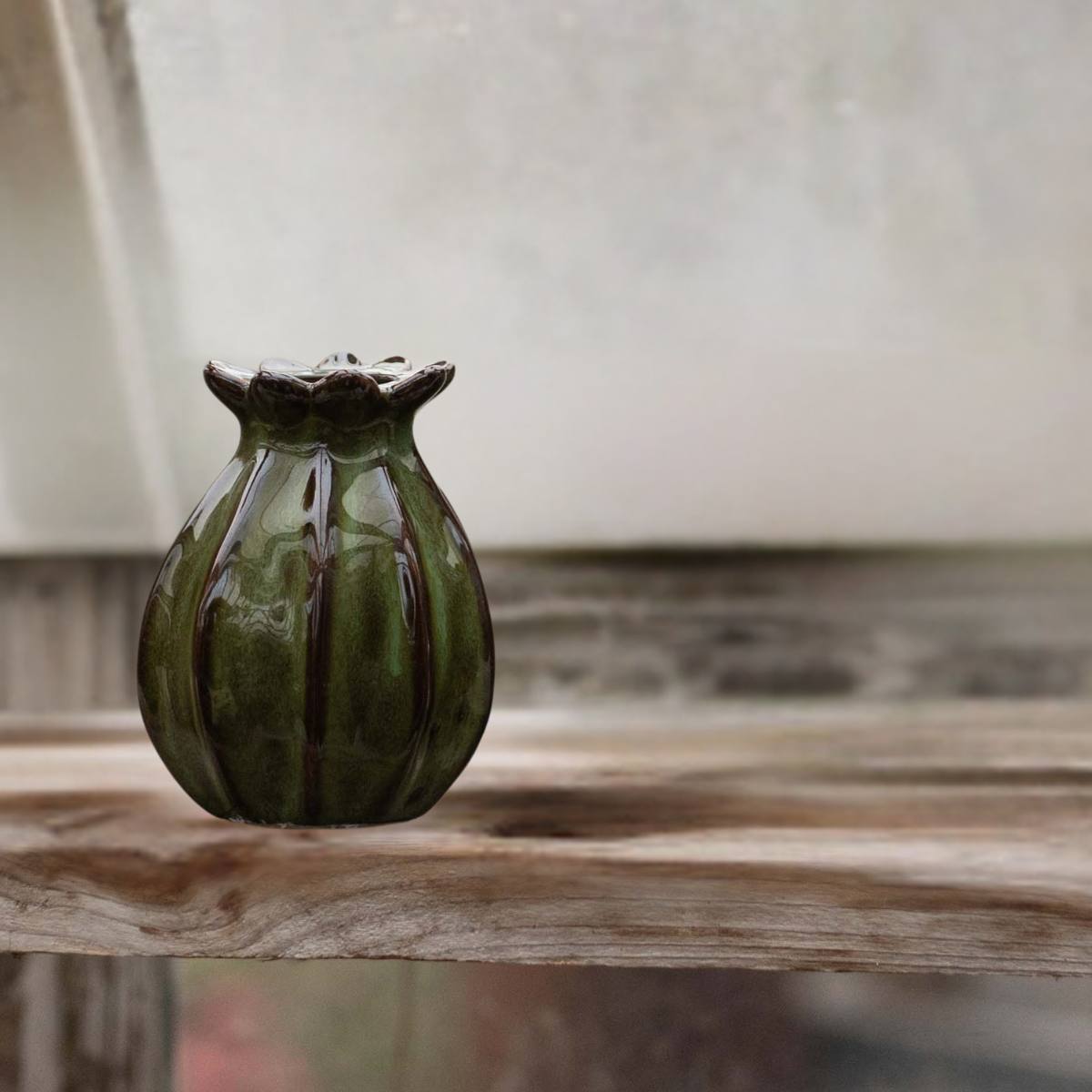 Lillian Vase – green stoneware vase with seed pod-inspired shape and fluted rim displayed on rustic wooden shelf