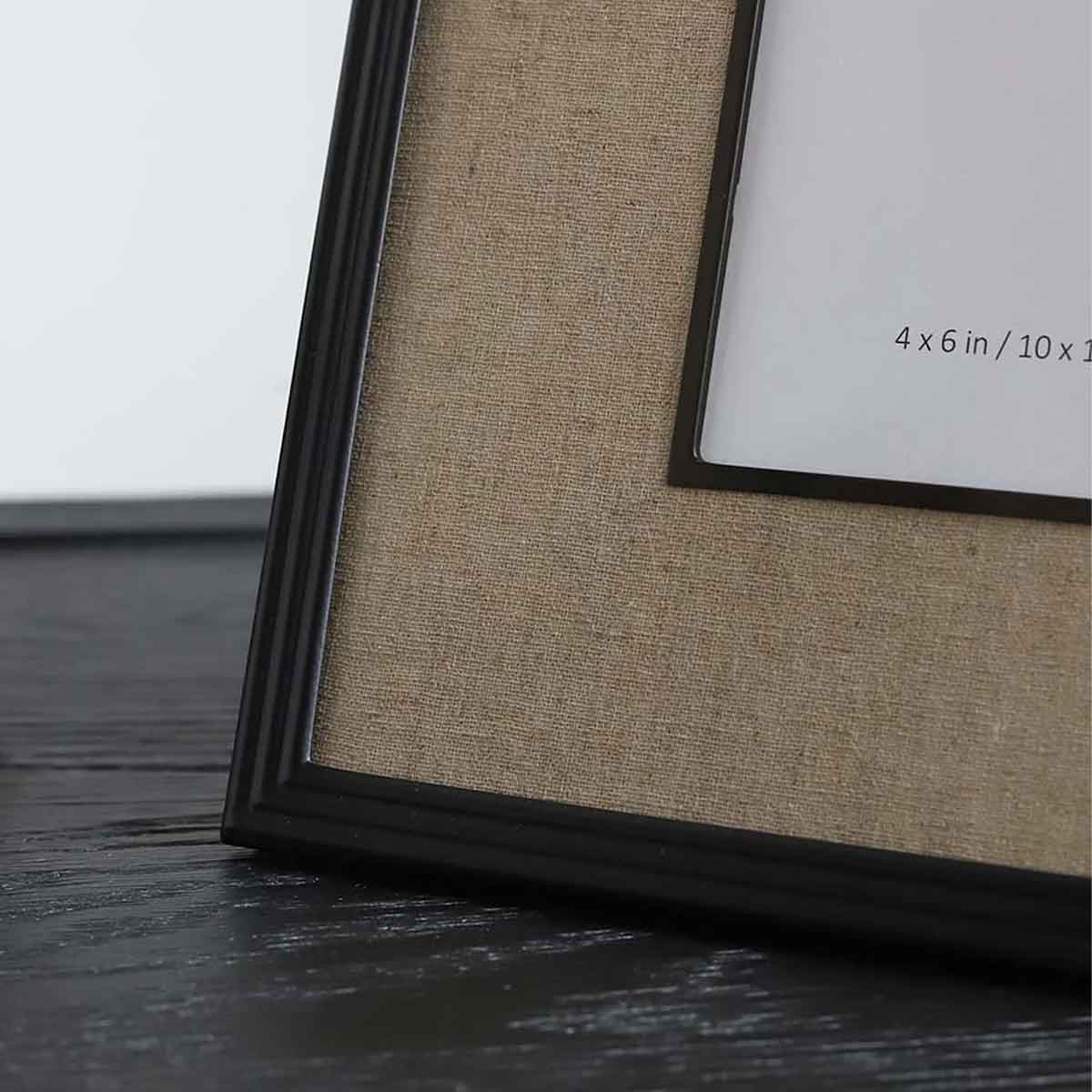 Close-up of black photo frame with a linen border displaying - 4×6 inch size- displayed on a table.