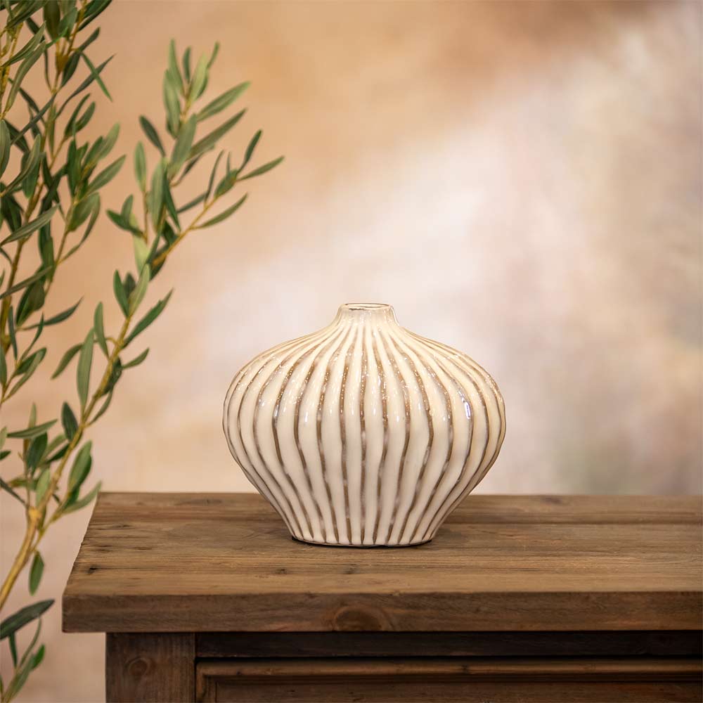 Decorative vase with ribbed texture on a wooden table with a blurred background