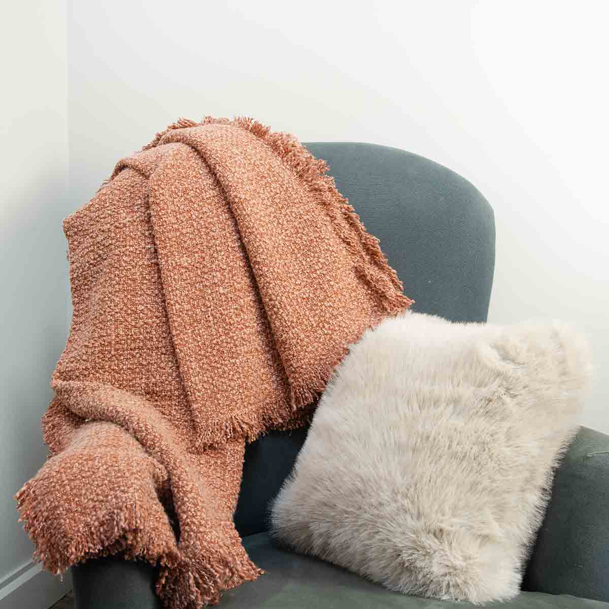 Terracotta Miraso cotton throw with fringe detailing draped over a dark chair
