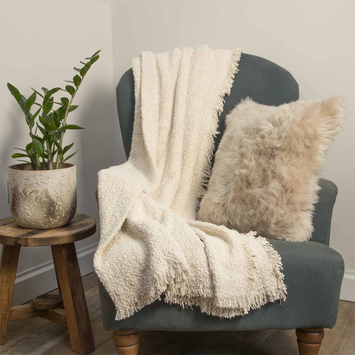 Miraso Throw in Natural Stone colour placed on chair with plant