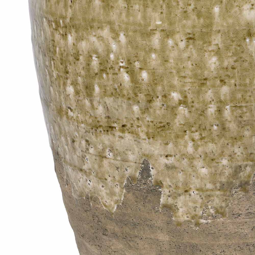 Close-up of a ceramic  vase showing a textured, speckled glaze in muted olive green and beige tones with a rougher unglazed base, isolated on a white background.