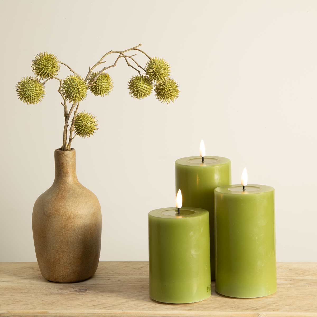 Trio of olive green flameless pillar candles with vase – LED wax candles styled indoors