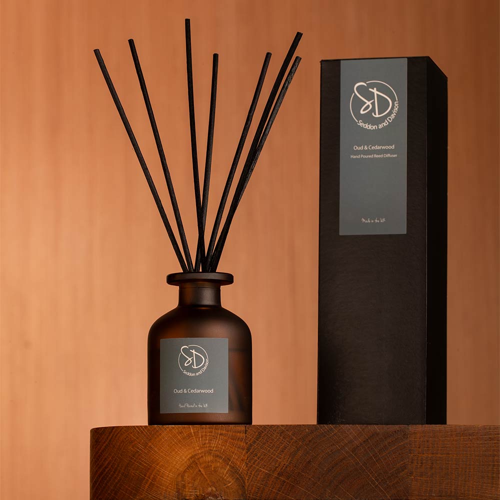Diffuser bottle with black sticks and packaging on a wooden surface