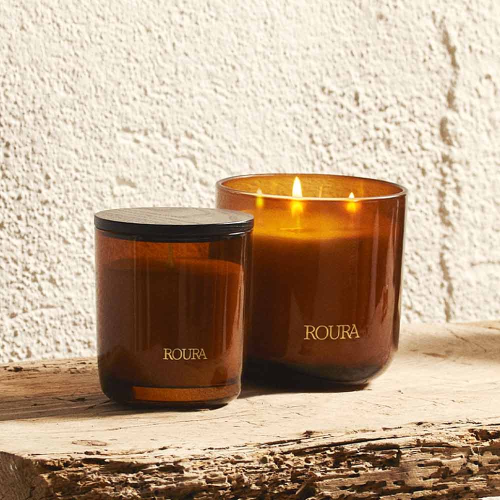 Royal Amber Glass Jar Candle by Roura with black lid on a wooden surface - shown with larger candle in same scent