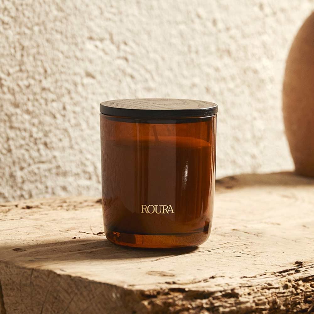 Royal Amber Glass Jar Candle by Roura with black lid on a wooden surface.