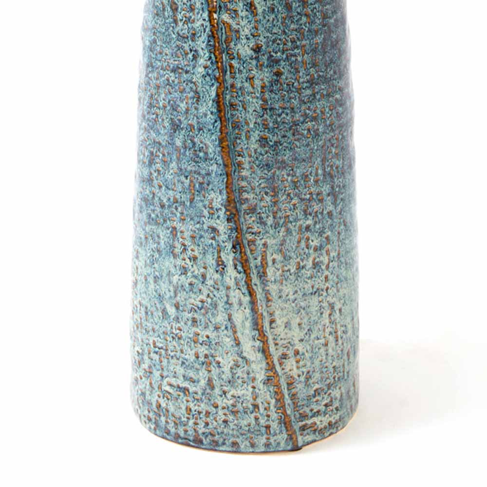 A close-up of a ceramic vase  with a textured, speckled blue and brown  glaze and a vertical brown ridge , shown against a plain white background.