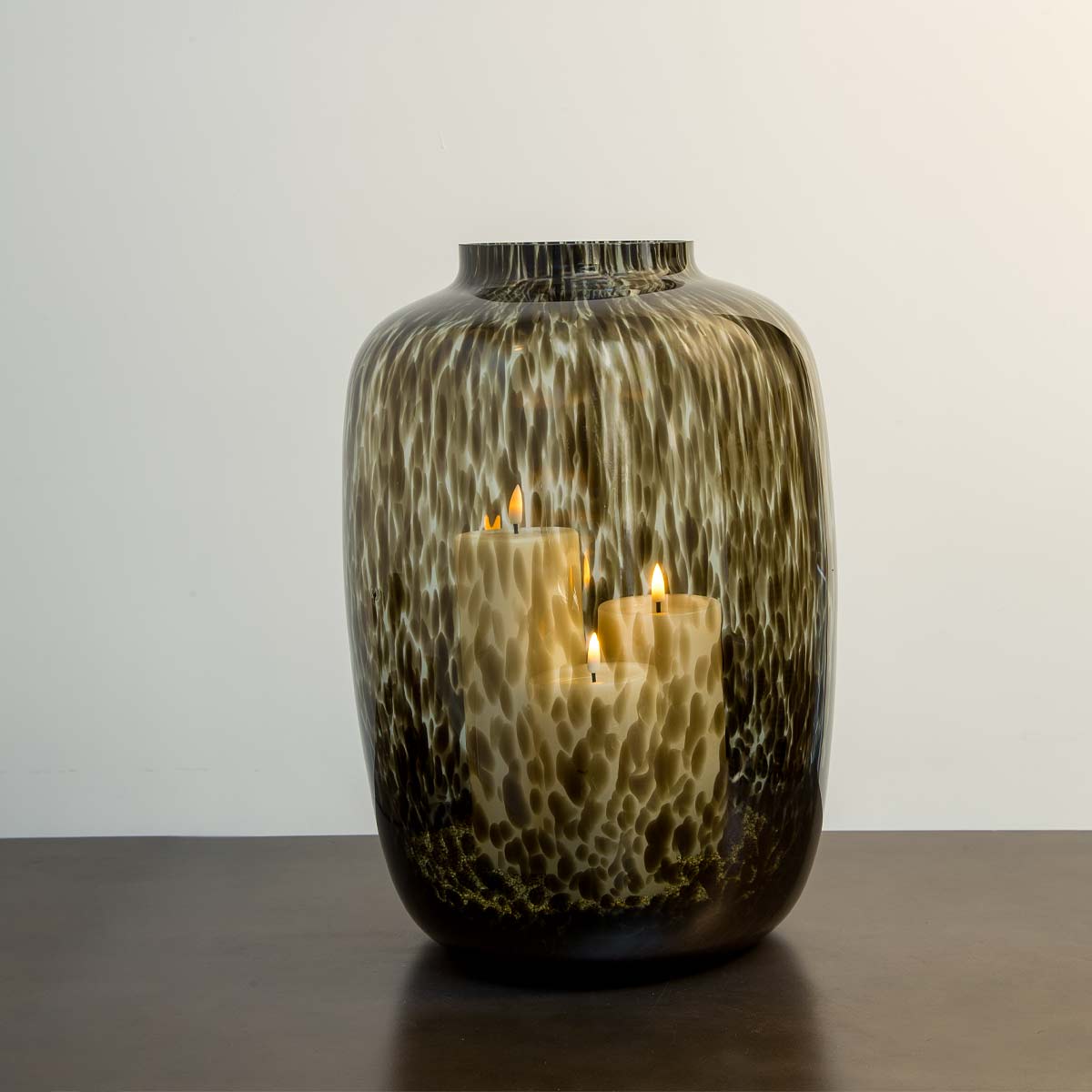Tall smoke-spotted cylinder glass vase with pillar candles inside