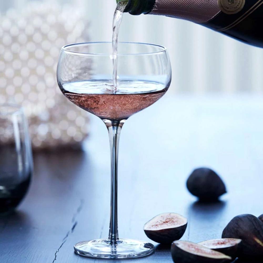 Elegant smoked cocktail glass, mouth-blown with a solid colour finish, displayed with pink moet champagne being poured.