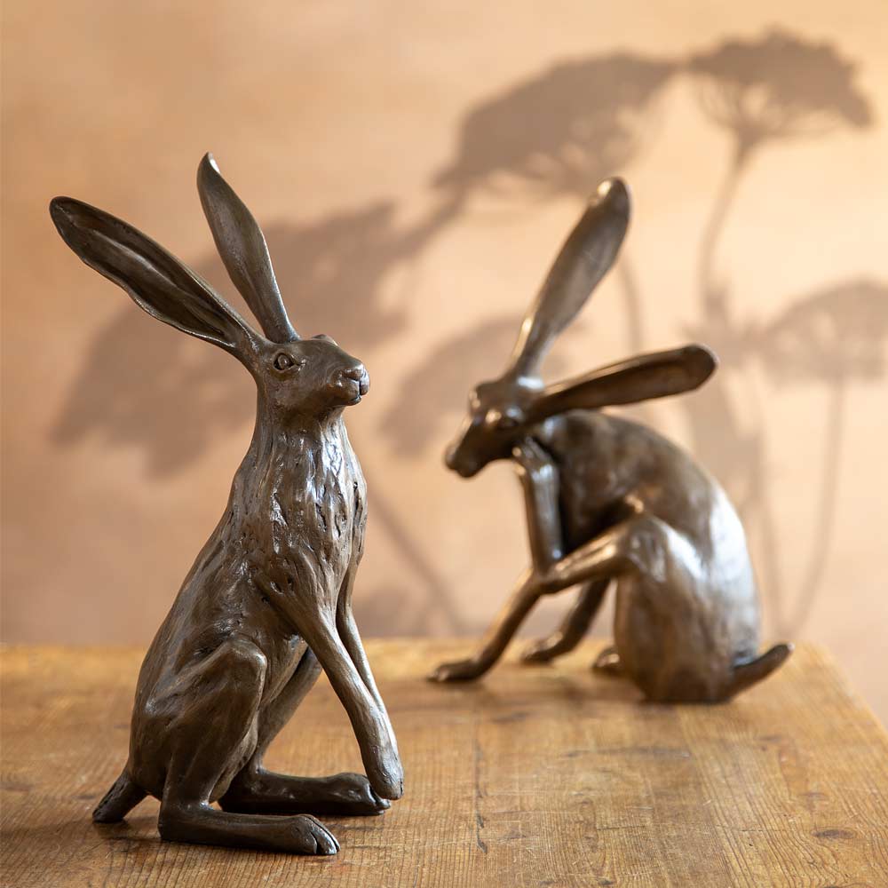 Startled Hare sculpture in bronze resin – handmade in the UK from original artwork by Joanna Martins - Displayed with candles and plants