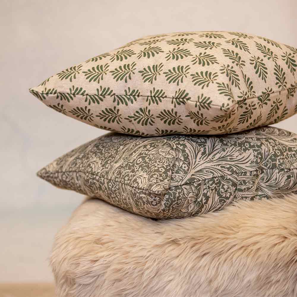Two patterned pillows stacked on a fur surface with a neutral background