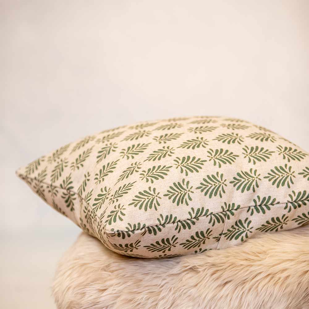 Decorative pillow with green leaf pattern on a beige background