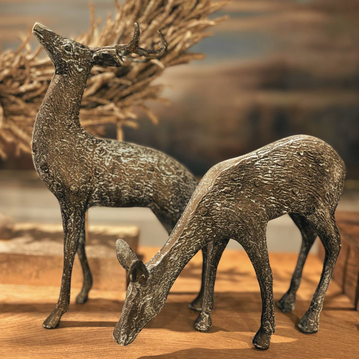 Bronze deer Theo and Kasper figurines on a wooden surface with a blurred natural background