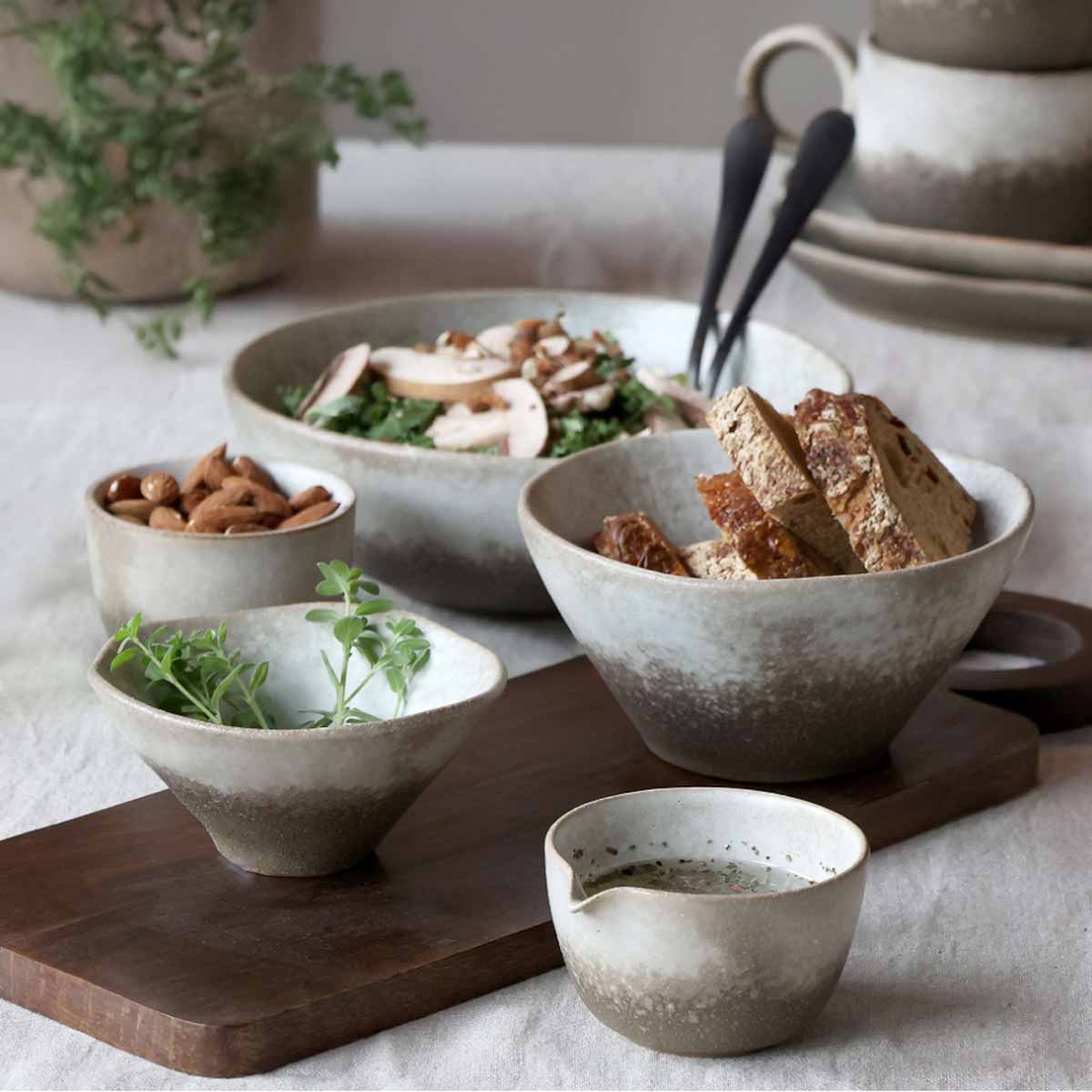 Valence Porcelain Bowls in Walnut – Two of the set of three styled with salad, bread, and dip on a rustic wooden board