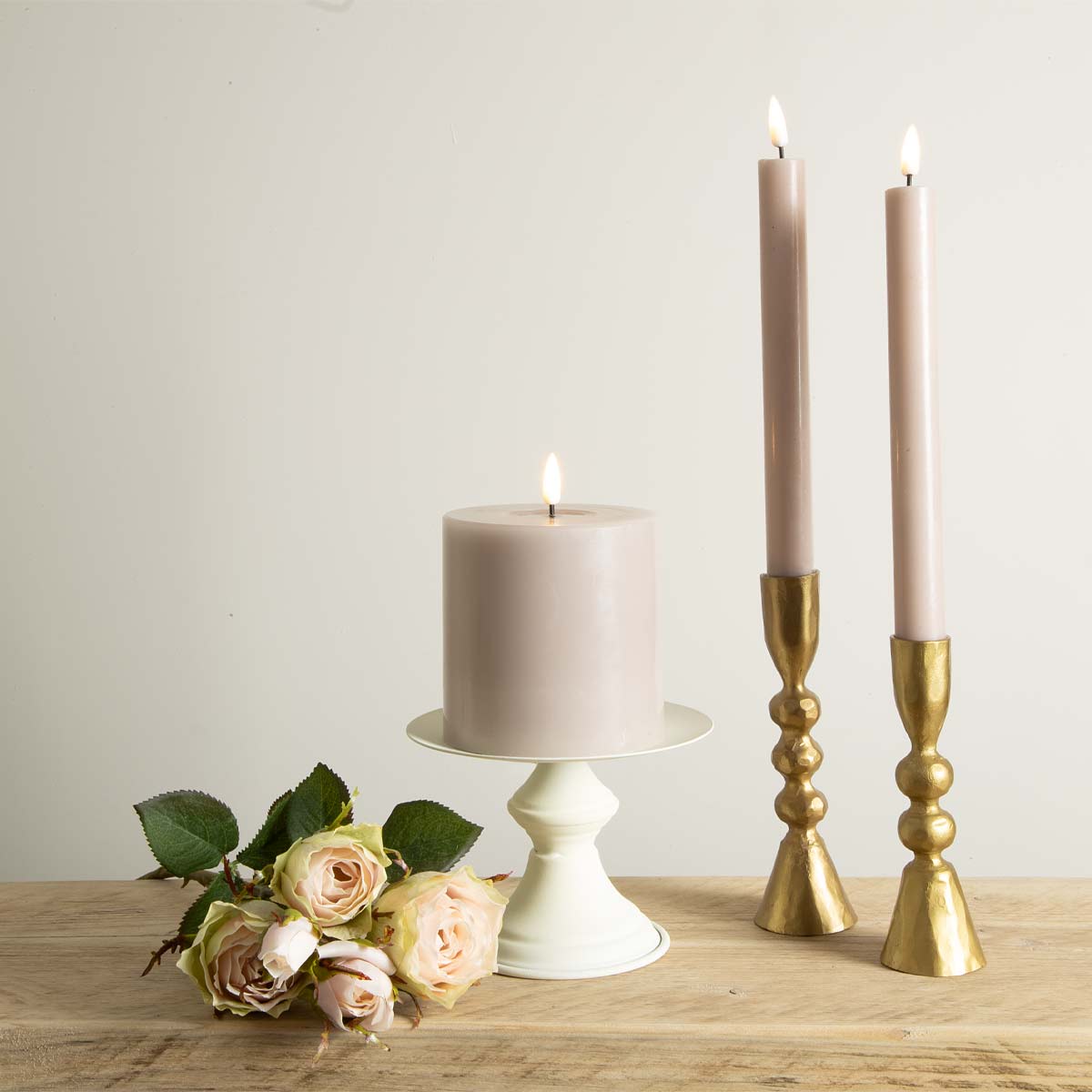 Pale rose LED dinner and pillar candles styled with gold holders and faux roses